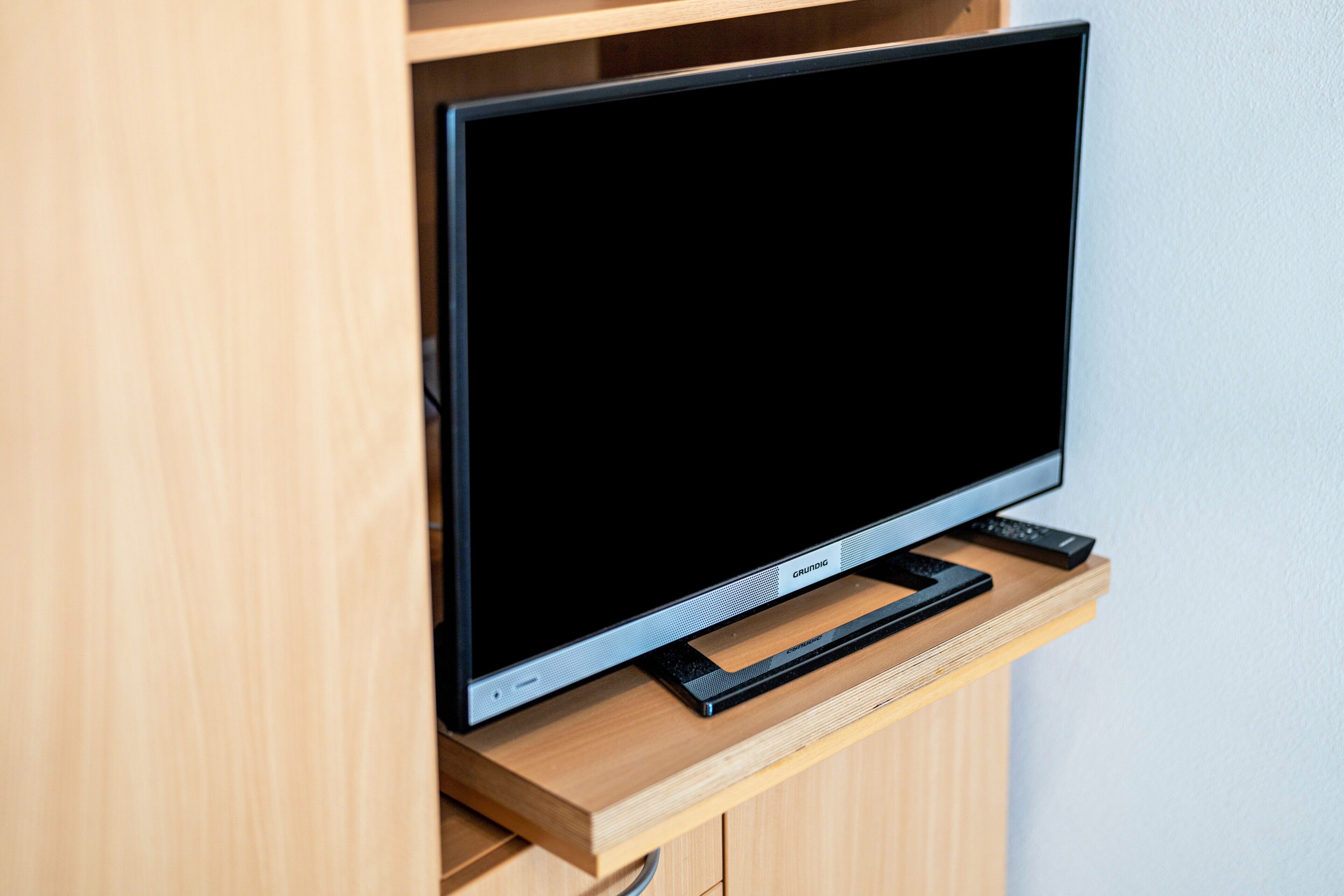 A flat-screen TV on a wooden stand.