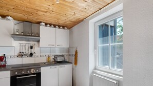 Una cocina con armarios blancos, una estufa de acero inoxidable y una ventana con vistas.