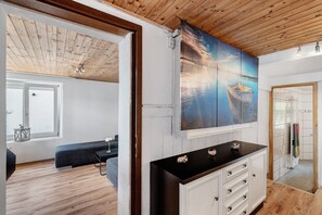 A room with a wooden ceiling, a large painting of a boat, a black countertop, and a view of a balcony.
