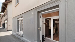 Un edificio con fachada gris, una puerta visible y una ventana.