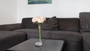 Un florero con flores sobre una mesa frente a un sofá.