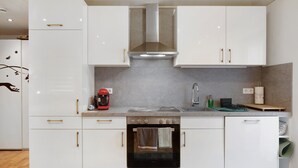 A modern kitchen with white cabinets, a stainless steel range hood, a built-in oven, and a sink. - Studio 'Gelis' with Mountain View, Private Terrace and Wi-Fi (Ihringen)