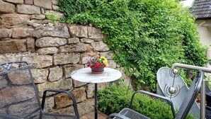 A stone wall, a metal table with a flower pot, and metal chairs. - Studio 'Gelis' with Mountain View, Private Terrace and Wi-Fi (Ihringen)