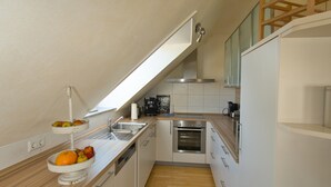 Una cocina moderna con armarios blancos, encimera de madera, horno integrado y cafetera.