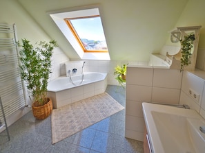 A modern bathroom with a skylight, a freestanding bathtub, a large mirror, and a potted plant. - Apartment 'Heidrun Kalkau' with Private Terrace, Balcony and Wi-Fi (Engstingen)