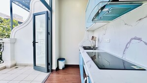 A modern kitchen with a marble countertop, a built-in oven, and a window with a view of the outside. - Anvi House - Vinhomes Marina (Hai Phong)