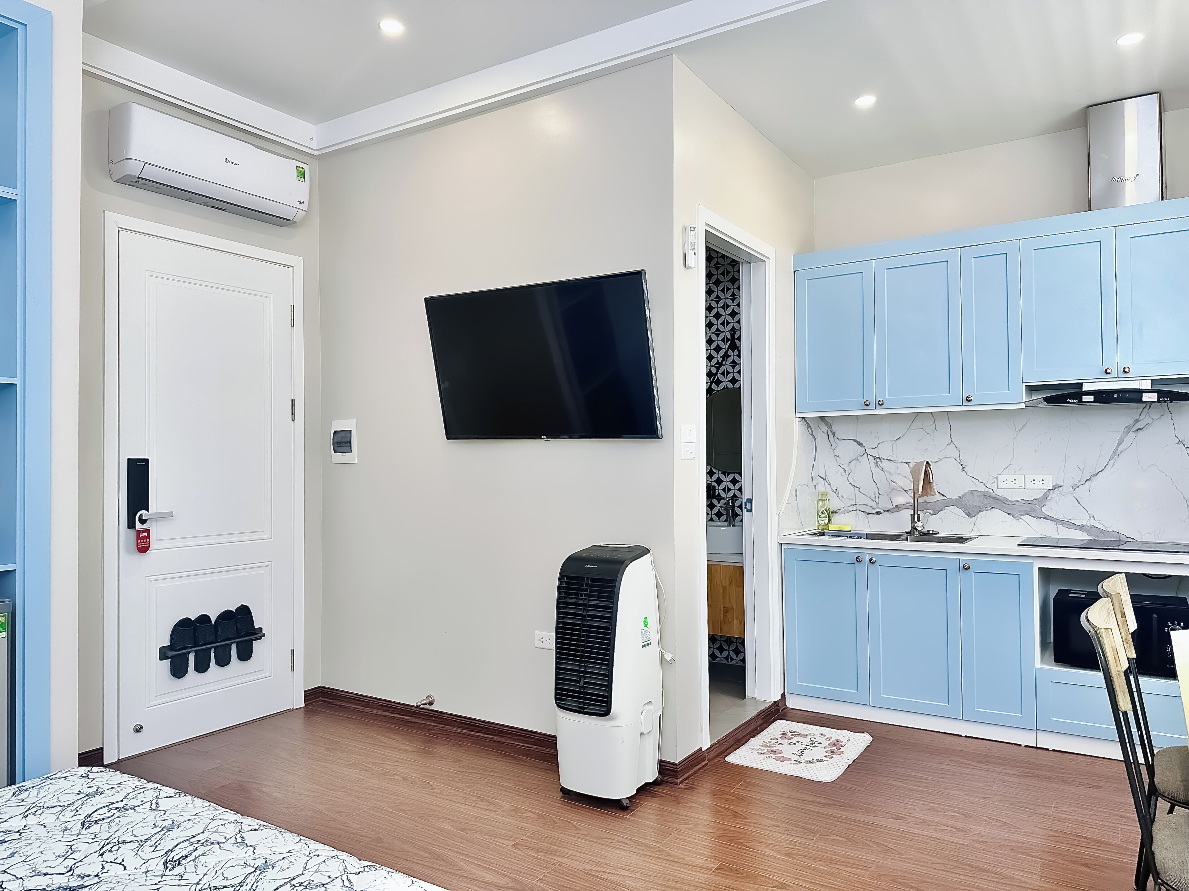 A modern kitchen with blue cabinets, a built-in oven, and a flat-screen TV.