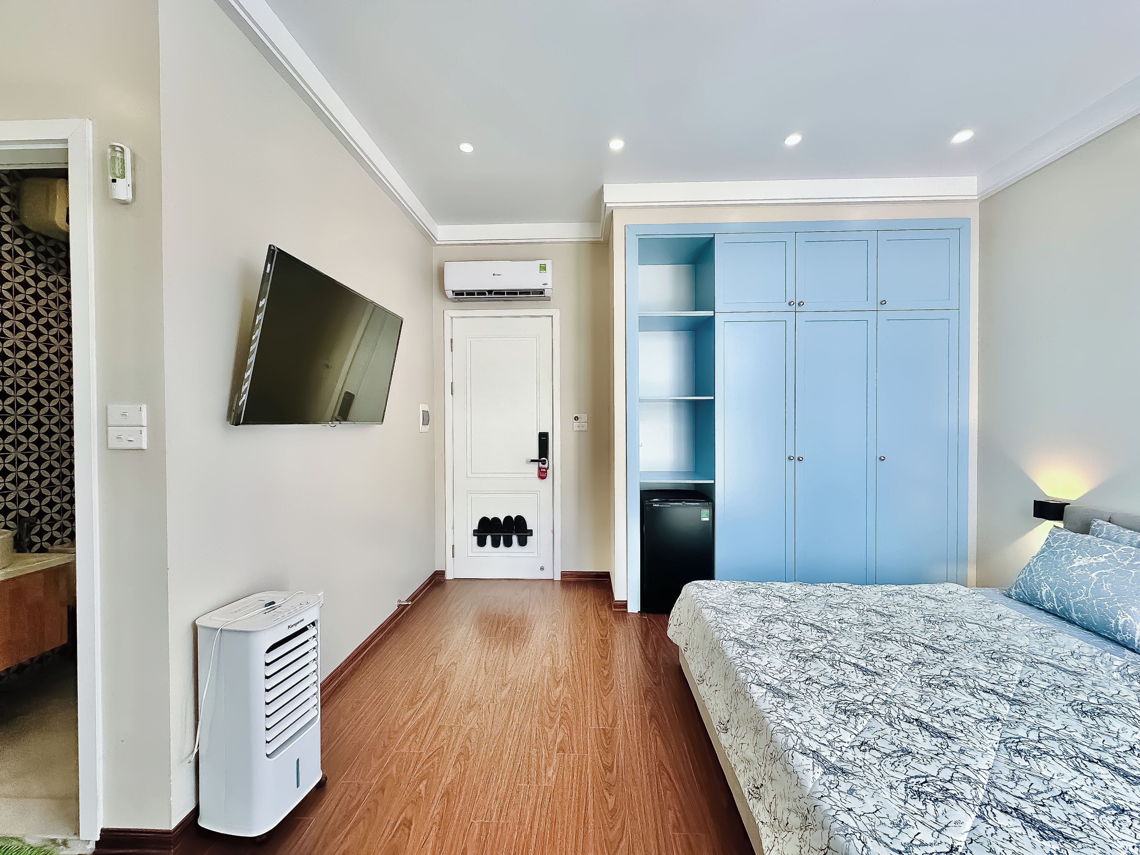 A bedroom with a bed, a wardrobe, a TV, and a heater.
