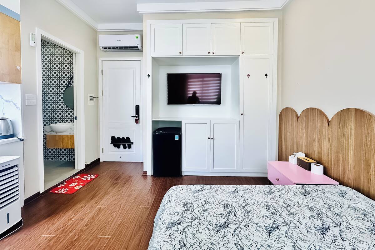 Ein Hotelzimmer mit Bett, Fernseher, Minibar, Waschbecken und Kleiderschrank.
