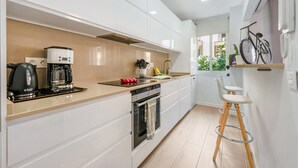Una cocina moderna con armarios blancos, cafetera, tostadora y una bicicleta en la pared.