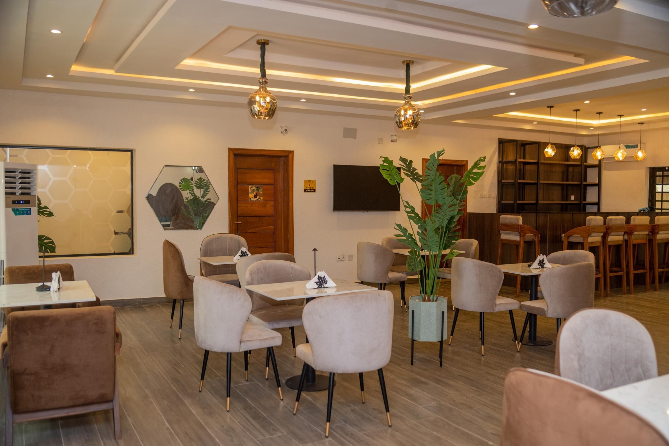 Un restaurante moderno con suelo de madera, sillas color beige e iluminación colgante.