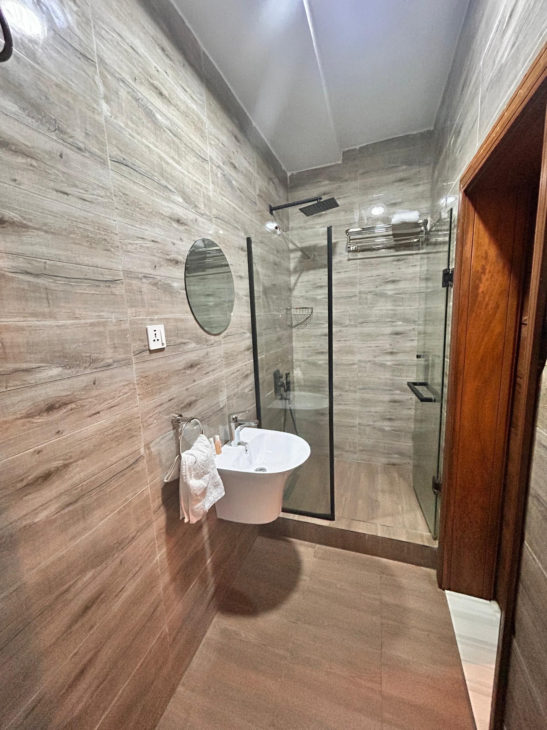 Une salle de bain moderne avec une baignoire sur pieds, une douche à parois de verre et un mur en marbre.