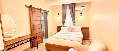 A bedroom with a bed, a chair, a mirror, and a wardrobe.