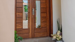 A wooden double door with a 'PUSH' sign, a potted plant, and a hanging light fixture.