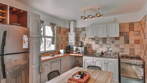 A compact kitchen with a refrigerator, microwave, stove, and a dining area with a table and chairs.