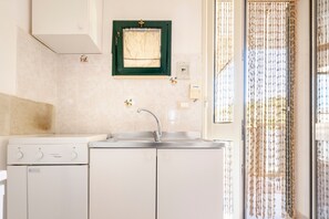 A kitchen with a stove, sink, and a window with a curtain.
