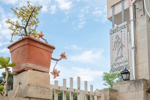 A terracotta pot with a flowering plant and a sign reading 'Welcome' above a building entrance.