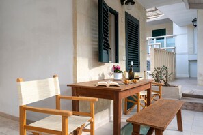 A wooden table with chairs, a bench, a potted plant, a wine bottle, and an open book.