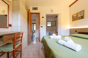 A hotel room with a bed, a chair, a desk, and a bathroom visible through an open door.