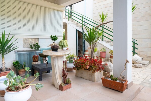 A courtyard with potted plants, a stone table, and a staircase.