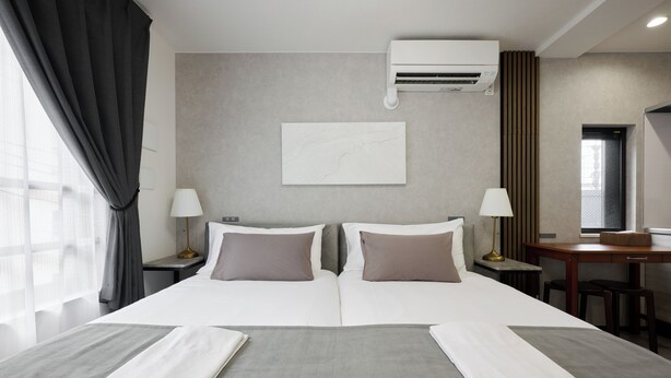 A hotel room with a large bed, two bedside tables, a desk, and an air conditioning unit. - RUTiLE IKEBUKURO TOKYO (Tokyo)