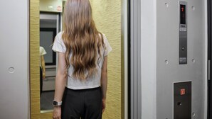 A woman standing in an elevator with a digital display showing an upward arrow and a button to press. - RUTiLE IKEBUKURO TOKYO (Tokyo)