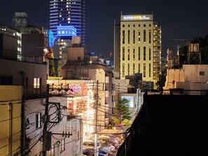 Un paisaje urbano nocturno con edificios iluminados, incluyendo un hotel llamado "Superhotel Premier" y otro edificio con un letrero azul.