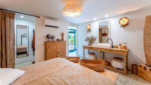Une chambre à coucher avec un lit, une commode en bois, une coiffeuse avec un miroir et une fenêtre donnant sur un beau paysage.