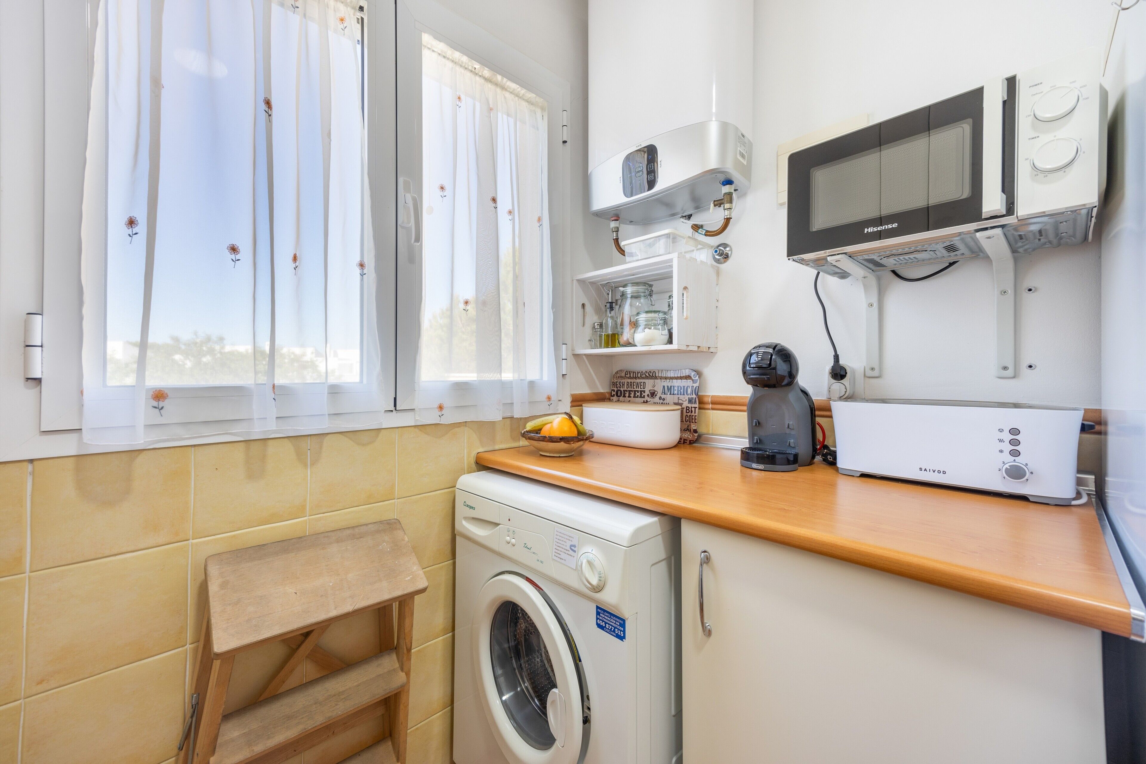 Una cocina compacta con lavadora, microondas y cafetera.