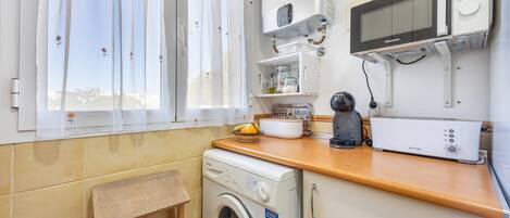 Una cocina compacta con lavadora, microondas y cafetera.