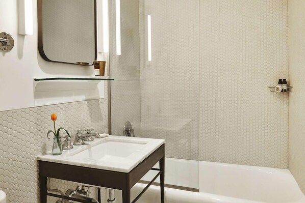 A bathroom with a white sink, mirror, and shower.