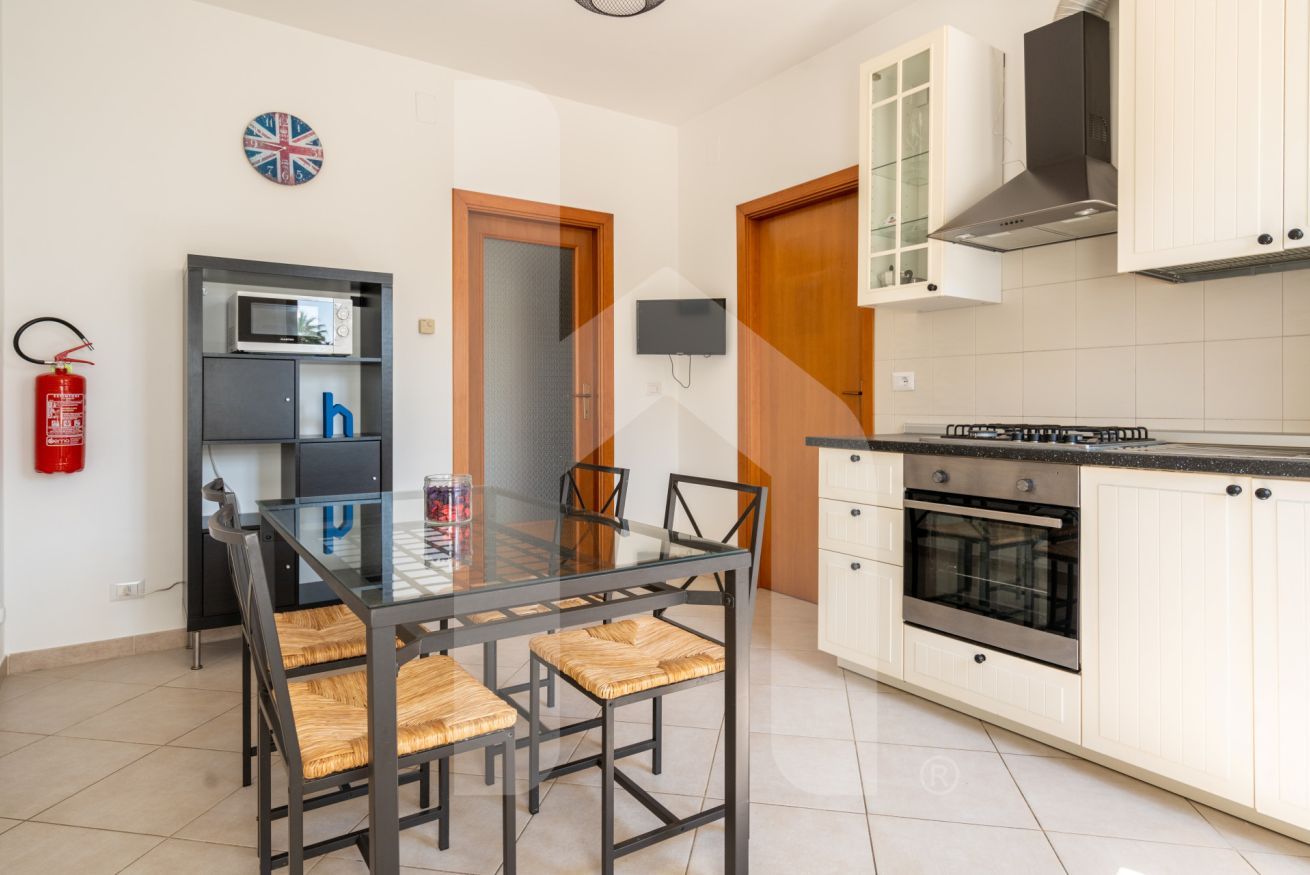 Una cucina moderna con mobili bianchi, un piano di lavoro nero e un forno integrato.