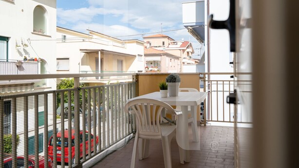 A balcony with a table and chairs, a view of neighboring buildings, and a metal fence. - Homiday - Via Gramsci Int. 4, 3-room apartment on the 1st Floor (Pineto)