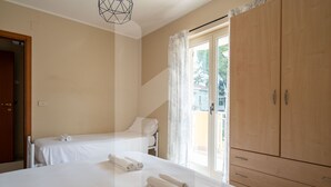 Ein Schlafzimmer mit zwei Betten, einem Holzschrank und einem Fenster mit Vorhängen.