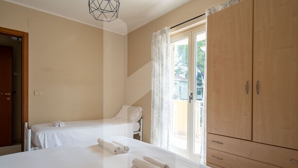 Un dormitorio con dos camas, un armario de madera y un ventanal con cortinas.