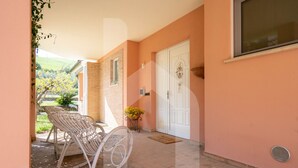 A porch with a rocking chair, a white door, and a potted plant. - Homiday - Villino Dei Poeti (Pineto)