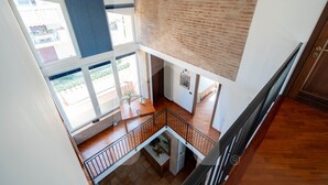 A multi-level interior with a wooden staircase, a brick wall, and a view of the outside. - Homiday - Villino Dei Poeti (Pineto)
