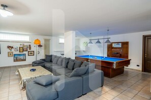 Un salon avec une table de billard, un canapé et une table basse.