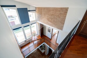 Un intérieur à plusieurs niveaux, avec un plancher en bois, un mur en briques et un balcon offrant une vue dégagée.