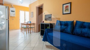 A living room with a blue sofa, a TV, and a dining area with a table and chairs. - Homiday - Via Gramsci Int.8, 3-room apartment on the 2nd Floor (Pineto)