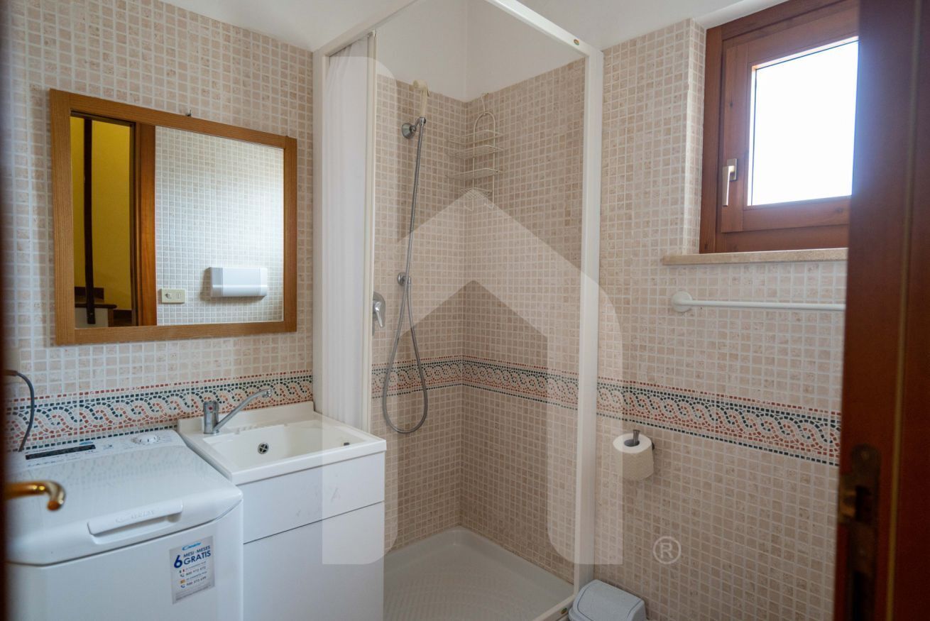 A bathroom with a shower, a sink, a toilet, and a mirror.