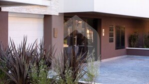 A modern building with a garage door, a glass entrance, and a paved driveway. - Homiday - Residence Pinetina Int. 02 (Pineto)