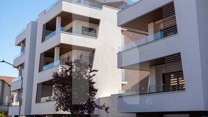 A multi-story residential building with balconies, large windows, and a clear sky. - Homiday - Residence Pinetina Int. 02 (Pineto)