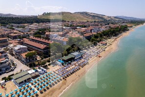 An aerial view of a coastal town with a beach lined with umbrellas and buildings. - Homiday - Pinetina Residence, Ext. 02 (Pineto)
