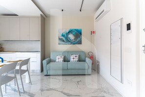 A modern living room with a sofa, a painting, and a fire extinguisher.