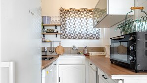 A kitchen with white cabinets, a Bosch oven, and a patterned curtain. - Apartment 'Montsant' with Sea Views, Private Terrace and Air Conditioning (Creixell)