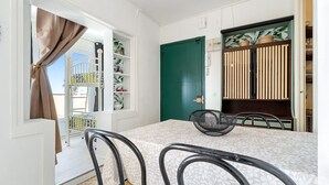 A dining area with a table, chairs, a green door, and a shelf with plants. - Apartment 'Montsant' with Sea Views, Private Terrace and Air Conditioning (Creixell)