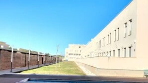 Een zwembad naast een gebouw met een bakstenen muur en een heldere lucht.