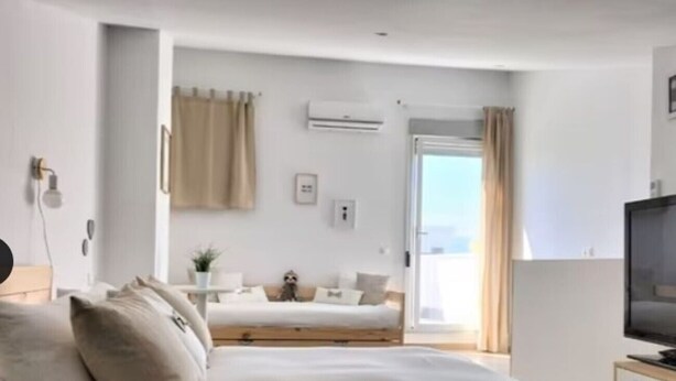 Een hotelkamer met een bed, een televisie, een bank en een raam met gordijnen.