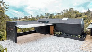 A modern building with a flat roof, a covered outdoor area, and a gravel ground.